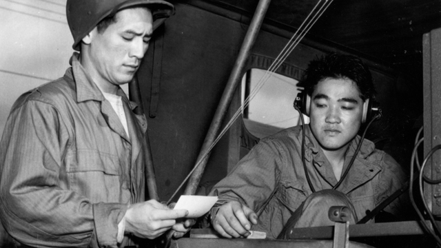 Sgt. Robert Oda takes a message for transmittal from Sgt. Edward Matsuda. 1943.